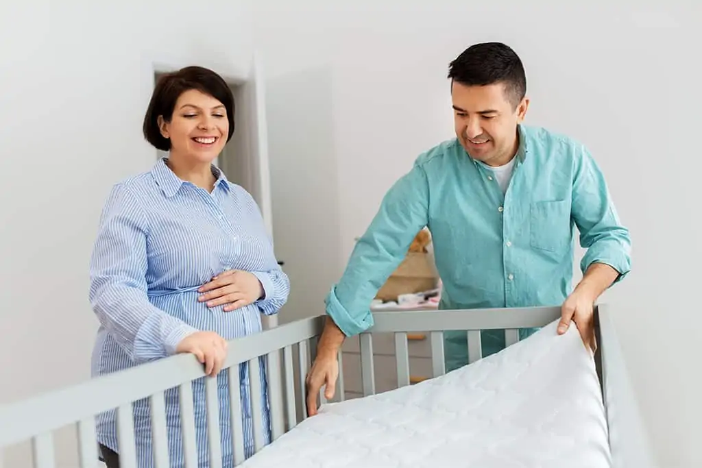 Parents installing crib mattress